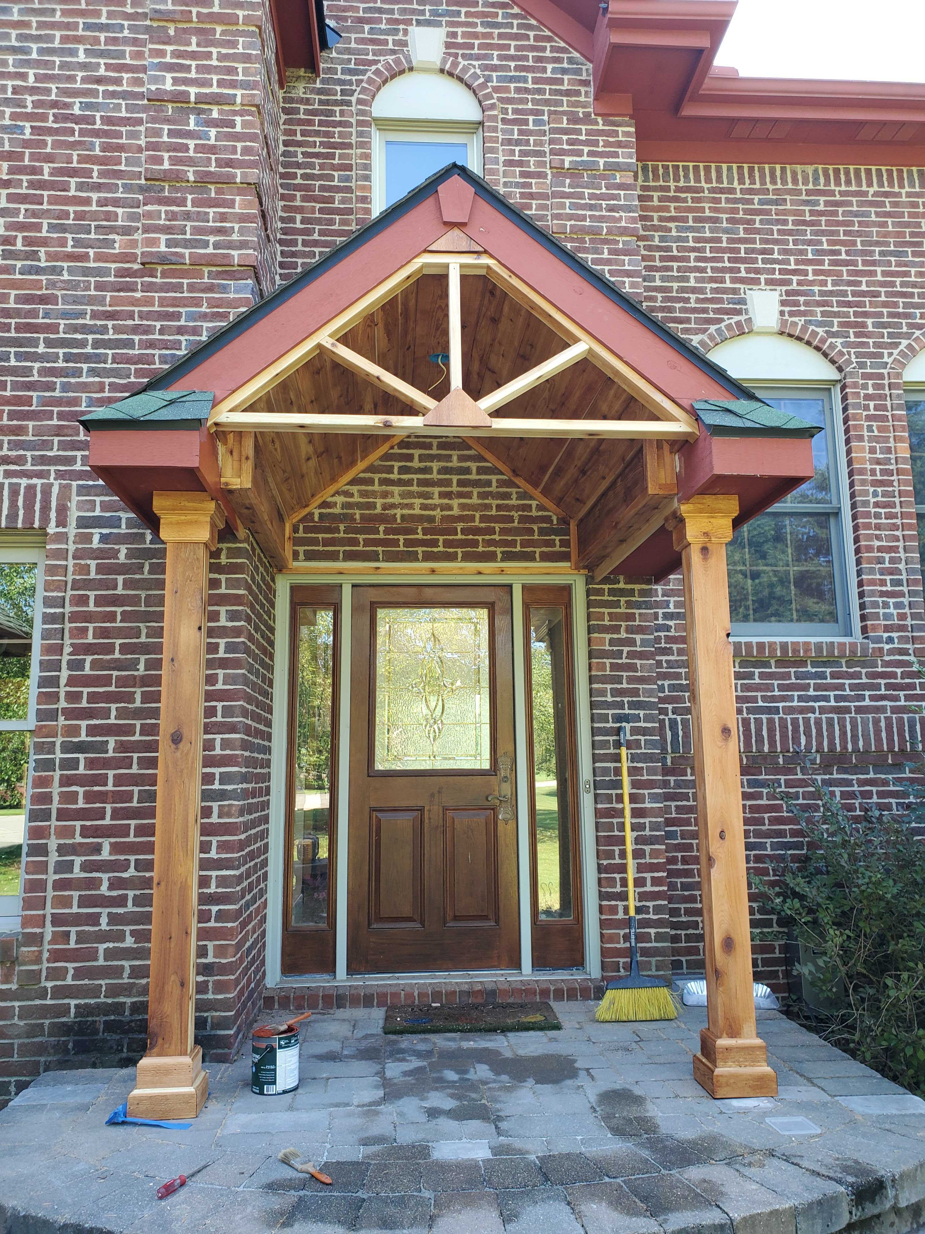 A custom awning on the porch of a brick house.